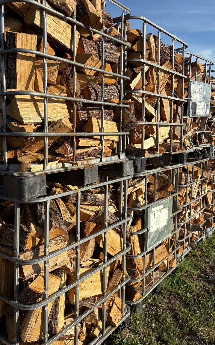 Gitterboxen mit gespaltenem Brennholz zum Trocknen aufgestellt